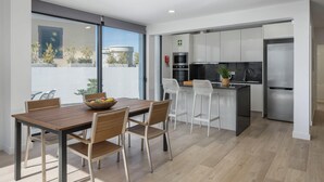 Una cucina moderna con elettrodomestici in acciaio inossidabile, un'area pranzo con mobili in legno e vista sull'esterno.