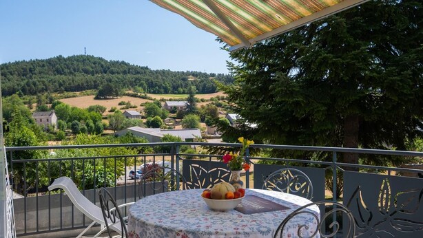 A balcony with a table, chairs, and a bowl of fruit. - Gîte Betty in Laval du Tarn (LAVAL DU TARN)
