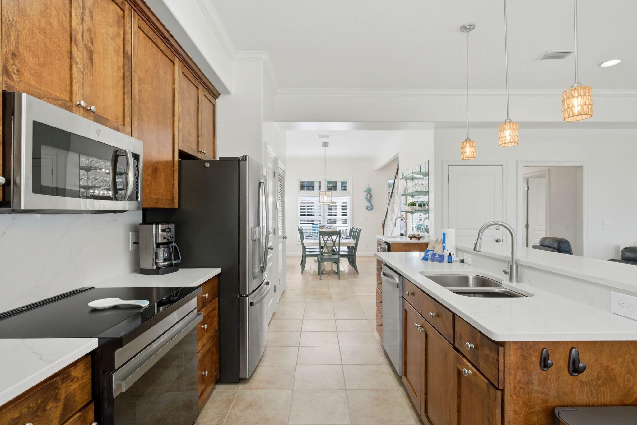 A modern kitchen with wooden cabinets, stainless steel appliances, and pendant lighting.