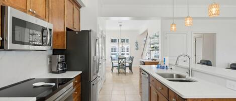 A modern kitchen with wooden cabinets, stainless steel appliances, and pendant lighting.