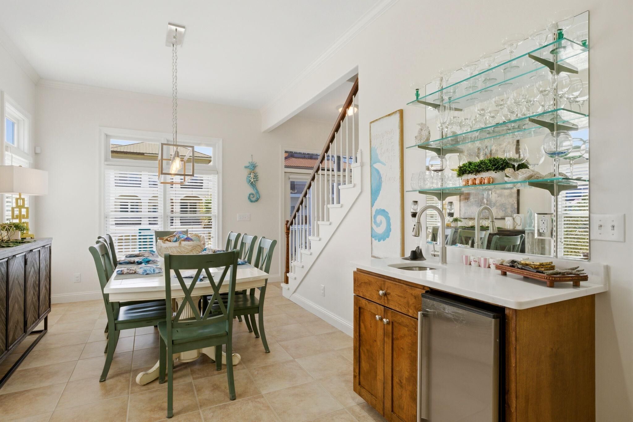 A kitchen with a dining table, chairs, a staircase, and a glass display shelf.