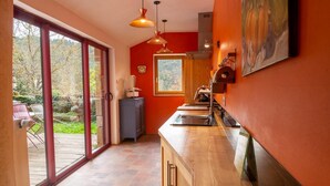 Een keuken met een grote schuifdeur naar een terras, een houten aanrecht en een rode wand.