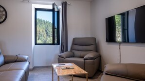 Ein modernes Wohnzimmer mit einer Ledersofa, einem Relaxsessel, einem Holztisch und einem an der Wand befestigten Fernseher.