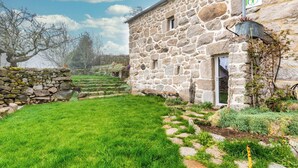 Un edificio in pietra con un cortile erboso, gradini in pietra e un cartello che indica un gîte.