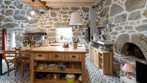 Una cucina rustica con pareti in pietra, travi in legno, un'isola centrale e un camino in pietra.