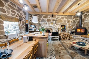 A rustic stone interior with a wooden dining table, a television, and a fireplace. - Gîte Castel Cailloux - LE PONT-DE-MONTVERT (LE PONT-DE-MONTVERT)