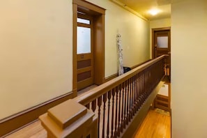 A hallway with wooden doors, a wooden railing, and a patterned floor. - City Oasis: Walk to Bars, Shops & SLC Attractions (Salt Lake City)