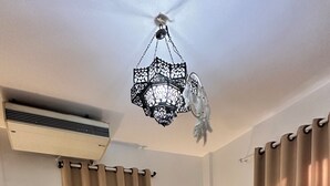 Makuuhuone, jossa on sänky, kaksi yöpöytää, lamppu, koristeellinen kattovalaisin ja verhot.