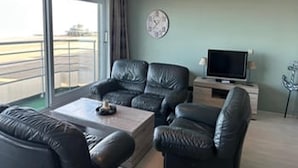 Uma sala de estar com um sofá, uma televisão e um relógio na parede.