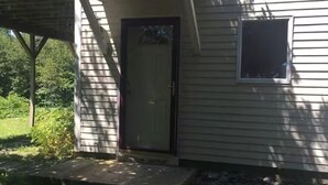 Een gelijkvloers huis met een voordeur, een klein raam en een veranda.