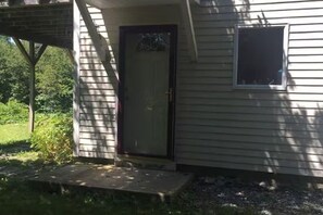 Ein eingeschossiges Haus mit Eingangstür, kleinem Fenster und einer Veranda.