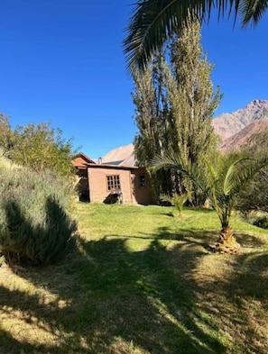 Una casa amb un sostre inclinat, envoltada d'un jardí ben cuidat i diversos arbustos.