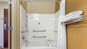Une salle de bain équipée d’une baignoire, d’une douche, d’un porte-serviettes et d’une porte donnant sur une autre pièce.
