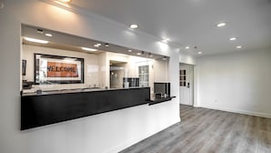 Un espace d’accueil moderne avec une enseigne « BIENVENUE », des spots encastrés au plafond et un plancher en bois.