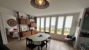 Een eethoek met een tafel, stoelen en uitzicht door grote ramen.