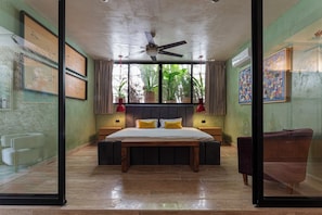 A bedroom with a bed, a ceiling fan, a window with curtains, and a view of greenery outside. - Casa Ya’ax | Colonial house, private pool & garden (Merida)