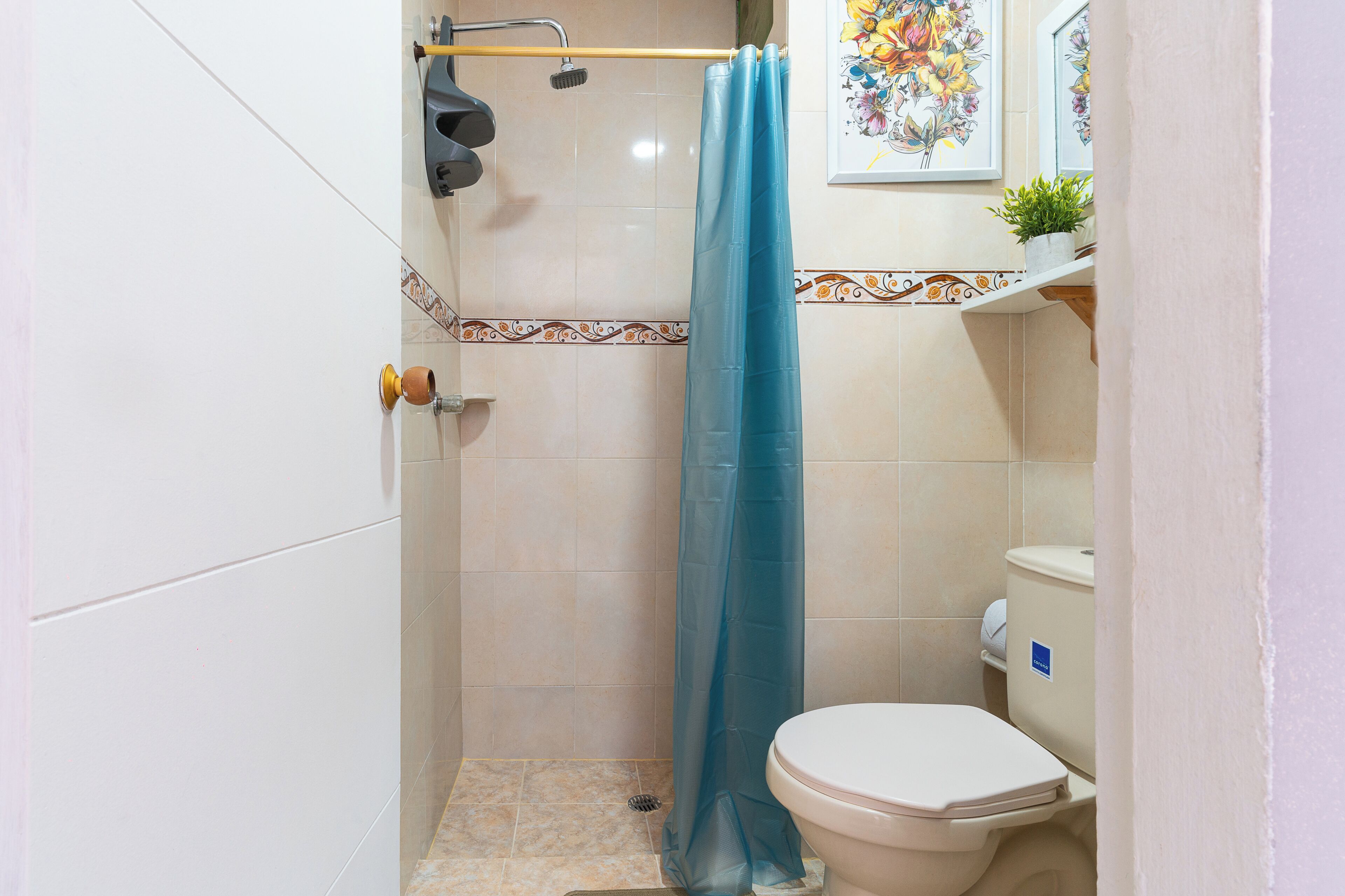 Une salle de bain équipée d’une douche, de toilettes et d’une bordure décorative en carreaux.