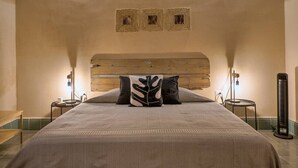 Une chambre à coucher avec un grand lit, une tête de lit en bois, deux tables de chevet et un luminaire fixé au mur.