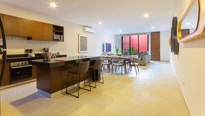A modern kitchen with a central island, dining area with chairs, and a large window.