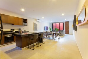 A modern kitchen with a central island, dining area with chairs, and a large window. - Casa Chak K`u | 2 bd | 2.5 bth | private pool (Merida)