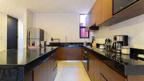 A modern kitchen with a black countertop, wooden cabinets, a built-in oven, and a coffee machine.