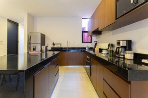 A modern kitchen with a black countertop, wooden cabinets, a built-in oven, and a coffee machine. - Casa Chak K`u | 2 bd | 2.5 bth | private pool (Merida)