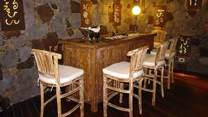 A bar area with a wooden counter, four wicker chairs with cushions, stone walls, and illuminated signs with Japanese characters. - Torre del Sol Charming Vacation Home (Guia de Isora)