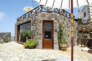 A stone building with a wooden door, large windows, and potted plants. - Torre del Sol Charming Vacation Home (Guia de Isora)