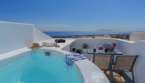 A rooftop terrace with a swimming pool, a welcome sign, a table with a basket of bread, and a view of the sea and distant landscape. - Fira Retreat With Sea Views (Santorini)