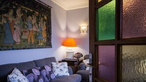 Ein Zimmer mit einer Couch, einer Lampe, einem Bild und einer Tür mit satiniertem Glas.
