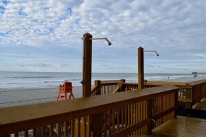 Une terrasse en bois avec une rambarde donnant sur une plage.