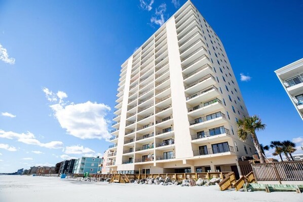 Un grand hôtel à plusieurs étages, doté de balcons, situé près d’une plage.