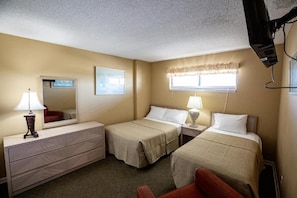 A hotel room with two beds, a dresser, a mirror, a window with curtains, and a television. - Beachfront 3BR Retreat w/ Balcony & Pool (Murrells Inlet)