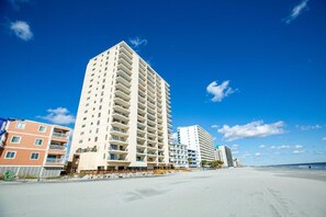 A beachfront hotel with multiple floors, balconies, and a sandy beach in the background. - Beachfront 3BR Retreat w/ Balcony & Pool (Murrells Inlet)