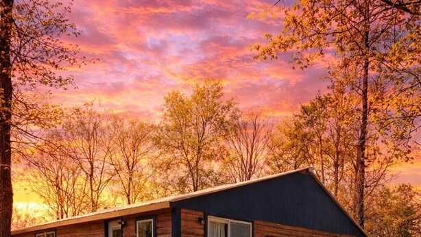Een vakantiehuisje van hout met een veranda, een deur en een klein raam.