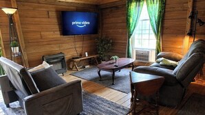 Een gezellig interieur van een chalet met een televisie, houten wanden, een open haard en een comfortabele zithoek.