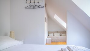 Une chambre à coucher avec un lit, un luminaire suspendu, une table de chevet et une vue sur une autre pièce.