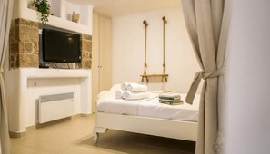 A bedroom with a bed, a television, a fireplace, and a swing. - Ano Mera Villa With Private Pool (Mykonos)