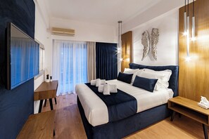 Une chambre d’hôtel moderne dotée d’un grand lit, d’un téléviseur à écran plat, d’une table de chevet en bois et d’un élément décoratif mural.