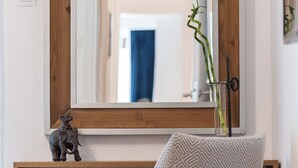 Ein modernes Badezimmer mit einem großen Spiegel, einem Holzkosmetikschrank, einem gemusterten Sessel und einer kleinen Elefant-Figur.