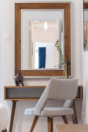 A modern bathroom with a large mirror, a wooden vanity, a patterned chair, and a small elephant figurine. - Acropolis Museum View Deluxe Apartment | 3 Falirou str 11742 Athens (Athens)