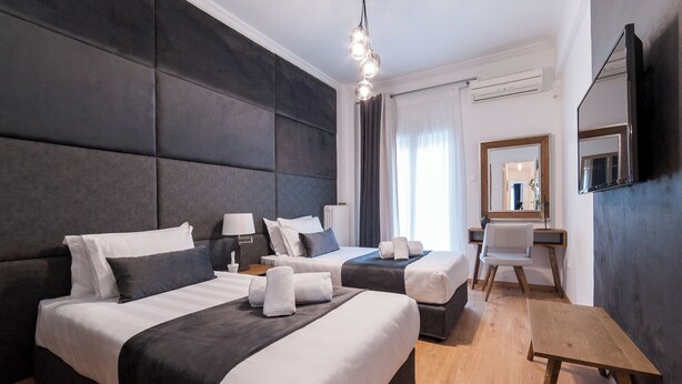 Ein Hotelzimmer mit zwei Betten, einem Schreibtisch, einem Stuhl, einem Spiegel und einer Pendelleuchte.