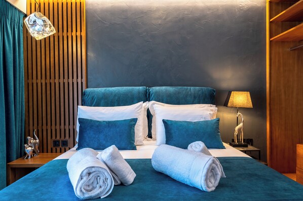 A hotel room with a bed, pillows, and a nightstand with a lamp. - Acropolis Museum View Executive Apartment | 3 Falirou str 11742 Athens (Athens)