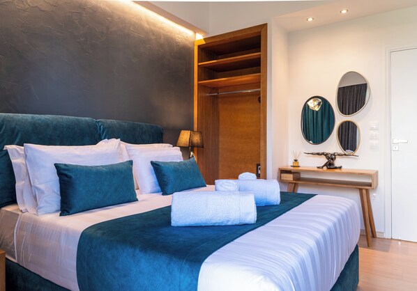 Een moderne hotelkamer met een groot bed, een houten garderobe, een bureau met spiegel en een wandlamp.