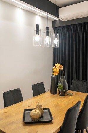 A modern dining area with a wooden table, black chairs, a vase with flowers, and pendant lights. - Acropolis Exclusive Apartment | 34 Dimitrakopoulou str 11742 Athens (Athens)