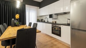 Une cuisine moderne avec des meubles blancs, un réfrigérateur en acier inoxydable, un four encastré et un four à micro-ondes.