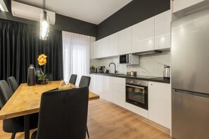 A modern kitchen with white cabinets, a stainless steel refrigerator, a built-in oven, and a microwave. - Acropolis Exclusive Apartment | 34 Dimitrakopoulou str 11742 Athens (Athens)