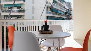 Un balcon avec une table ronde et deux chaises, un pot de fleurs et une rambarde.