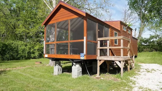 Eine Holzhütte mit großen Fenstern, einer Terrasse und einem Schild, das einen Mietpreis angibt.