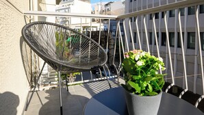 Un balcon avec une chaise en métal, une petite table et un pot de fleurs.